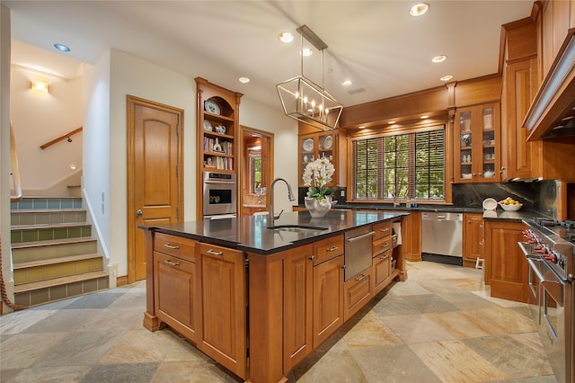 kitchen featuring appliances with stainless steel finishes, decorative light fixtures, sink, premium range hood, and a kitchen island with sink