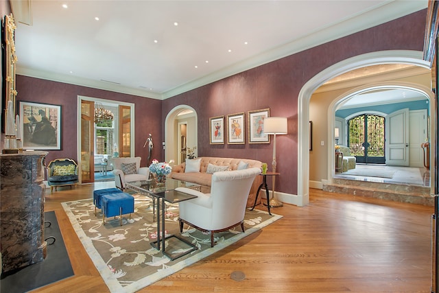 living room with french doors, ornamental molding, and light hardwood / wood-style floors