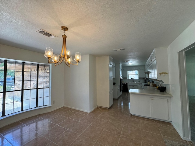 kitchen with an inviting chandelier, decorative light fixtures, kitchen peninsula, and white cabinets