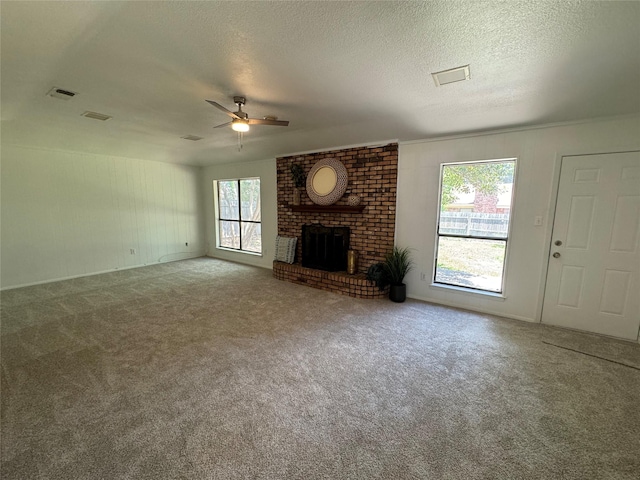 unfurnished living room with ceiling fan, carpet, a brick fireplace, and a textured ceiling