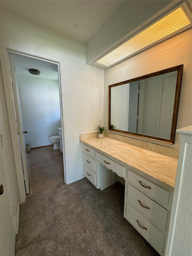 bathroom with vanity, toilet, tile patterned flooring, and a textured ceiling