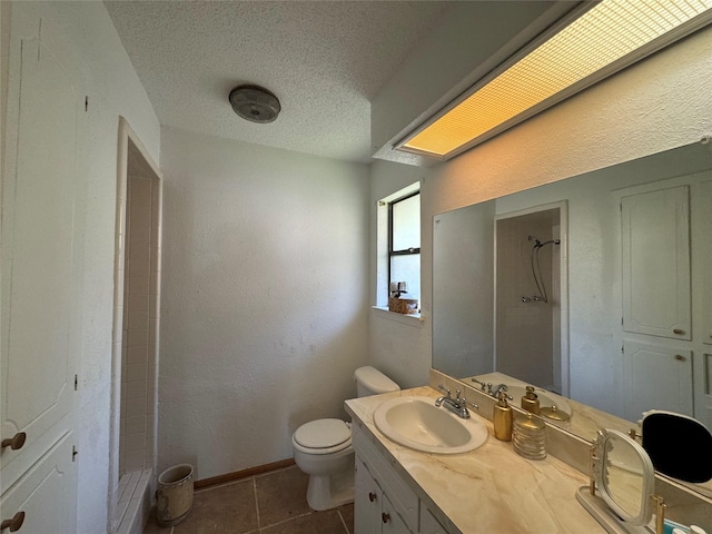 bathroom featuring tile patterned flooring, vanity, a textured ceiling, toilet, and walk in shower