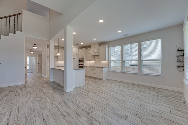 kitchen with light stone counters, stainless steel microwave, light hardwood / wood-style flooring, and pendant lighting