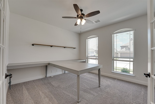 unfurnished office with ceiling fan and light colored carpet