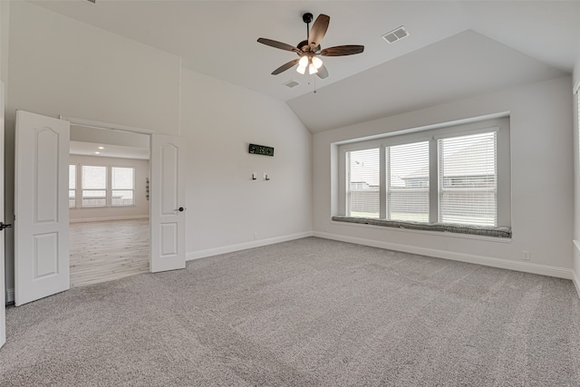 empty room with ceiling fan, lofted ceiling, carpet floors, and plenty of natural light