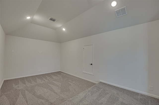 carpeted empty room featuring vaulted ceiling