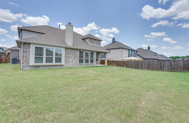 rear view of property with a yard and central air condition unit