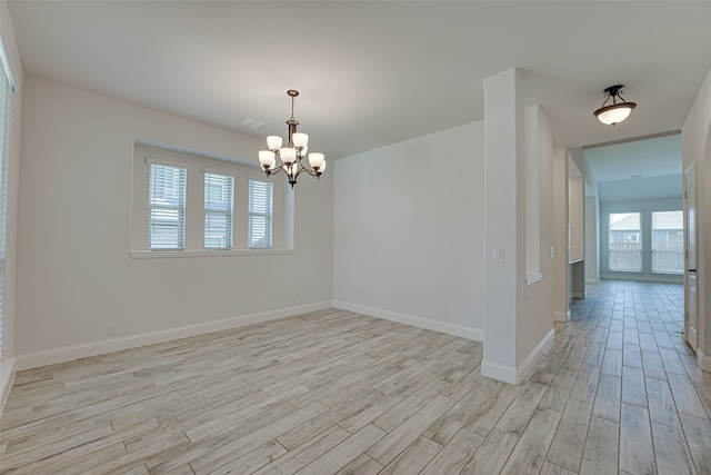 spare room featuring light hardwood / wood-style floors and a notable chandelier