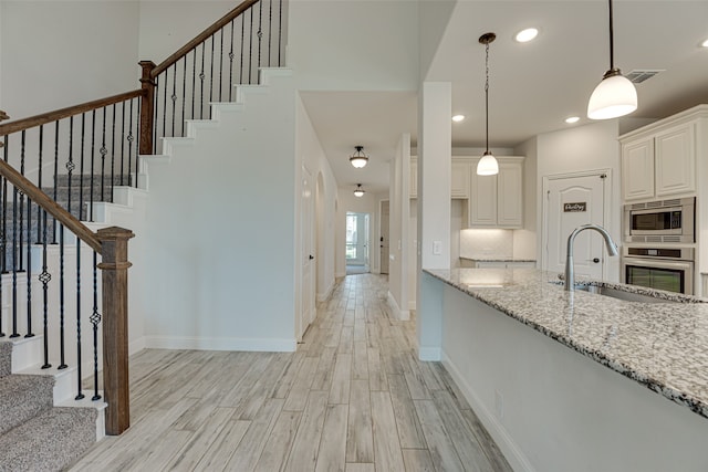 kitchen with light stone countertops, stainless steel appliances, white cabinets, and sink