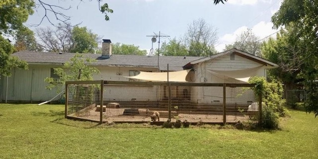 back of house featuring an outdoor structure and a lawn