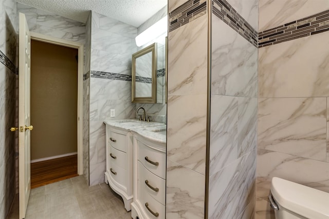 bathroom featuring vanity, hardwood / wood-style flooring, tile walls, toilet, and a textured ceiling