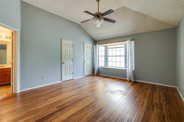 spare room featuring lofted ceiling, wood-type flooring, and a textured ceiling