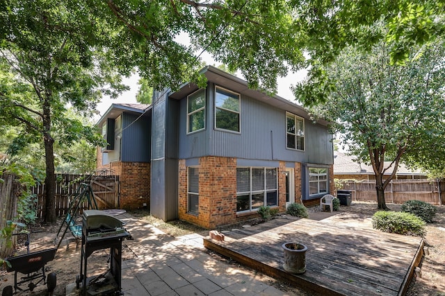 rear view of house featuring a deck, a patio, central AC unit, and an outdoor fire pit