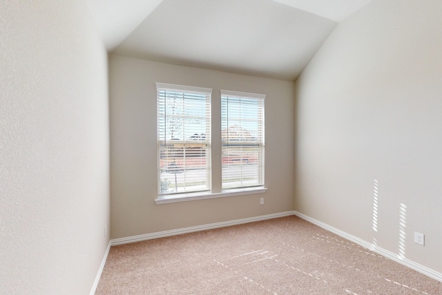 carpeted empty room featuring vaulted ceiling