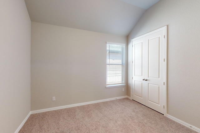 unfurnished bedroom featuring light colored carpet and vaulted ceiling