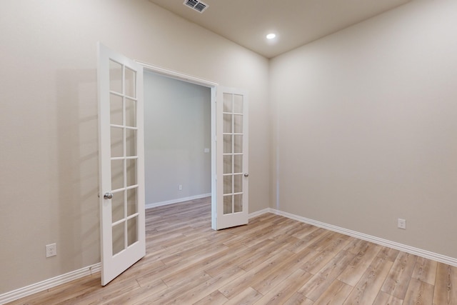 empty room featuring light wood-type flooring and french doors