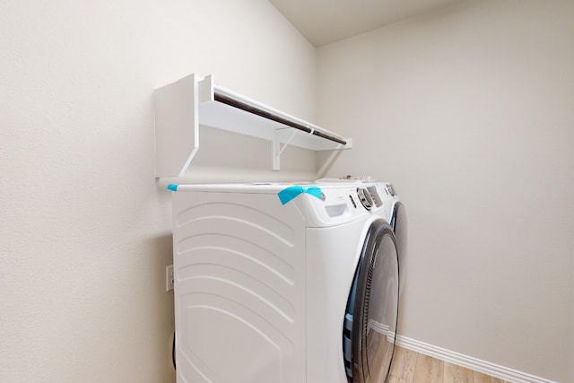 laundry area featuring washing machine and dryer and light hardwood / wood-style floors