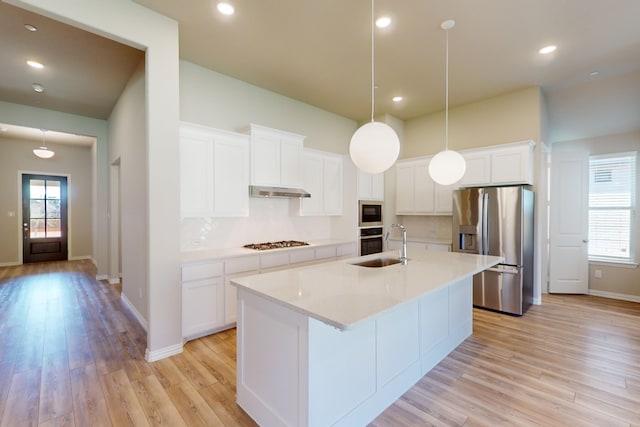 kitchen with stainless steel appliances, white cabinetry, plenty of natural light, and light hardwood / wood-style flooring