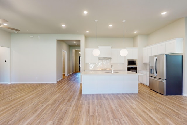 kitchen featuring light hardwood / wood-style flooring, backsplash, decorative light fixtures, white cabinets, and appliances with stainless steel finishes