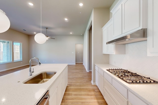 kitchen featuring light stone countertops, sink, appliances with stainless steel finishes, exhaust hood, and light wood-type flooring