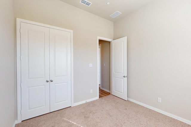 unfurnished bedroom with light carpet and a closet