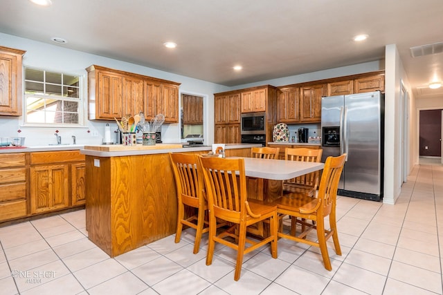 kitchen featuring light tile patterned floors, a center island, built in microwave, stainless steel fridge, and oven