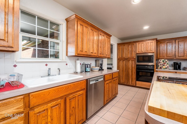 kitchen featuring stainless steel dishwasher, built in microwave, oven, sink, and backsplash