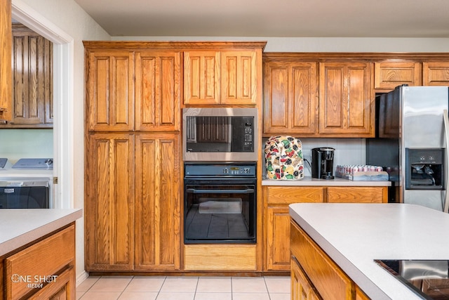 kitchen with washing machine and dryer, black appliances, and light tile patterned floors