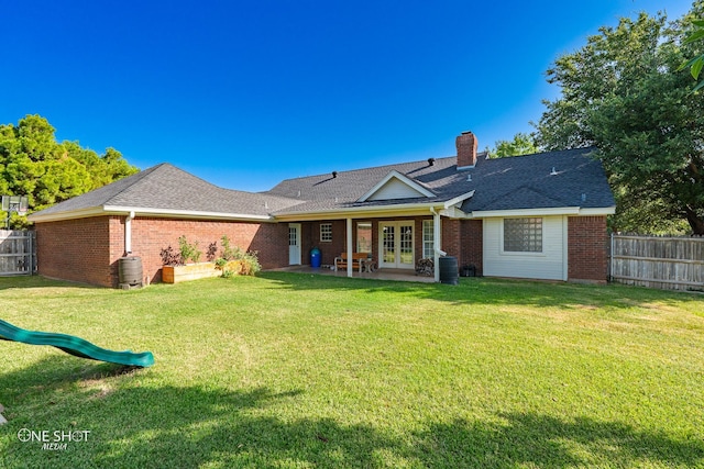 rear view of property with french doors, a lawn, and a patio area