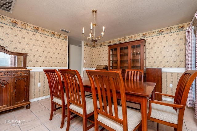 tiled dining area with an inviting chandelier and a textured ceiling