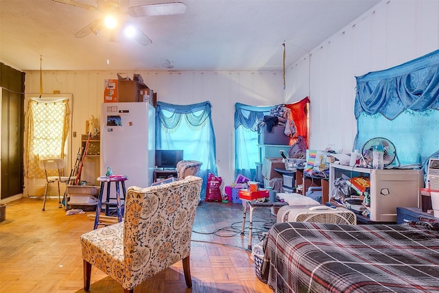 bedroom with white fridge, ceiling fan, wooden walls, and parquet flooring