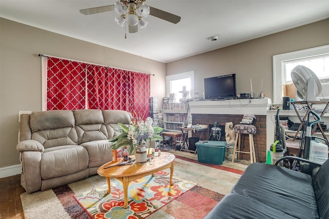 living room with a brick fireplace, hardwood / wood-style flooring, ceiling fan, and a healthy amount of sunlight