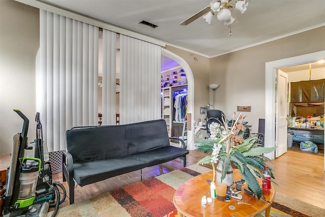 living room with ceiling fan, crown molding, and wood-type flooring