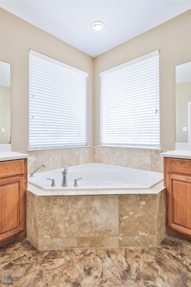 bathroom with a relaxing tiled tub, tile patterned floors, and vanity