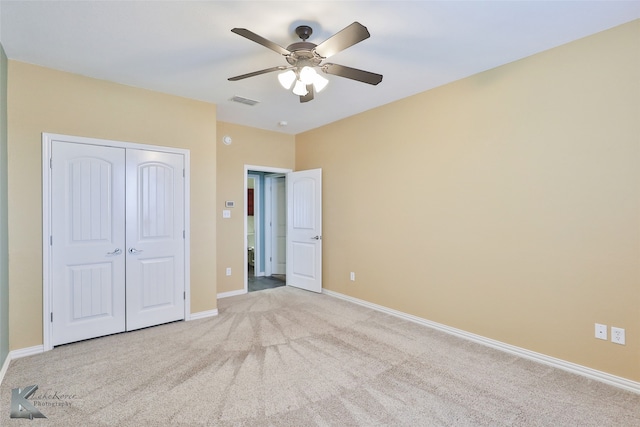 unfurnished bedroom with light carpet, ceiling fan, and a closet