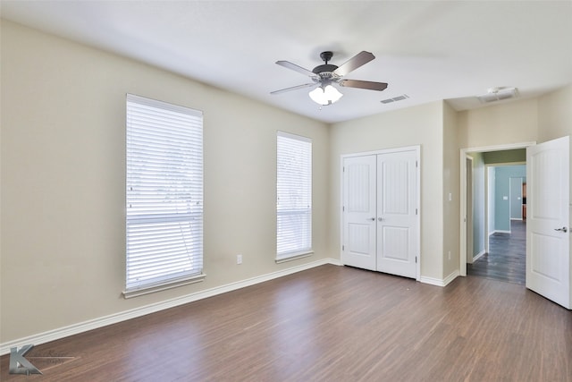 unfurnished bedroom featuring ceiling fan, dark hardwood / wood-style flooring, and a closet