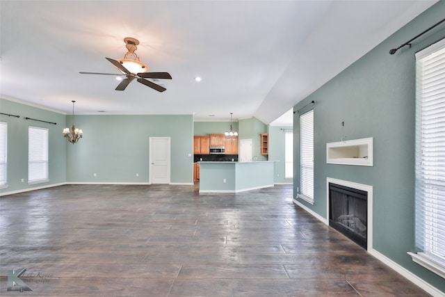 unfurnished living room with ceiling fan with notable chandelier and dark hardwood / wood-style floors