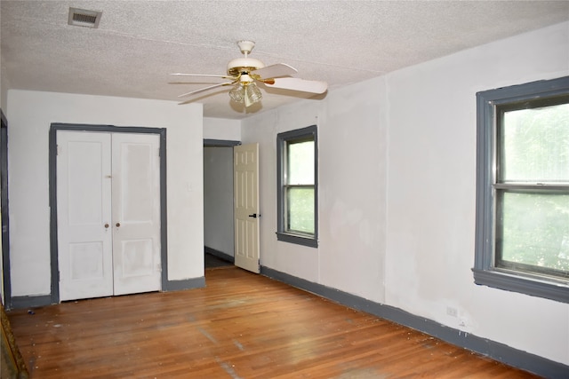 unfurnished bedroom featuring wood-type flooring, a textured ceiling, a closet, and ceiling fan