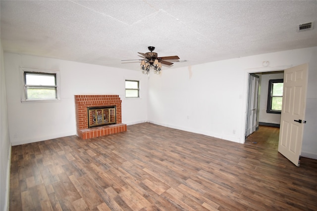 unfurnished living room featuring a textured ceiling, a brick fireplace, ceiling fan, and hardwood / wood-style floors