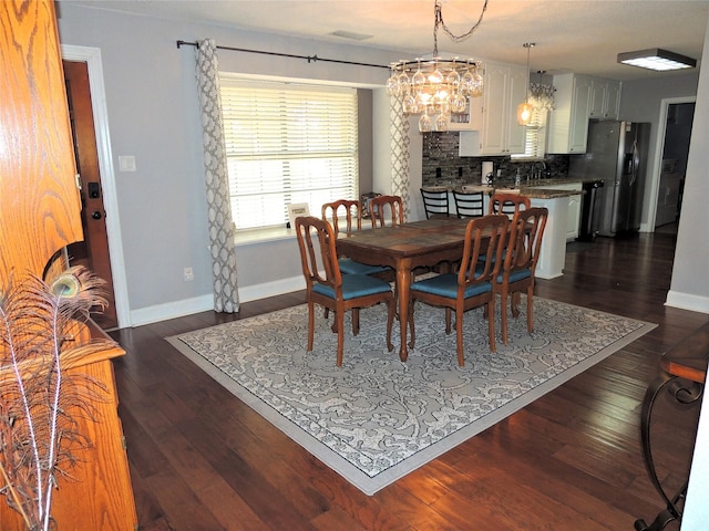 dining room with dark wood-type flooring and a notable chandelier