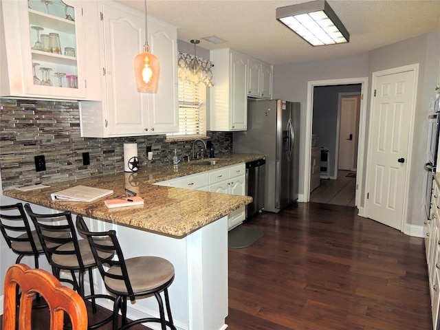 kitchen with sink, kitchen peninsula, hanging light fixtures, white cabinetry, and a breakfast bar area