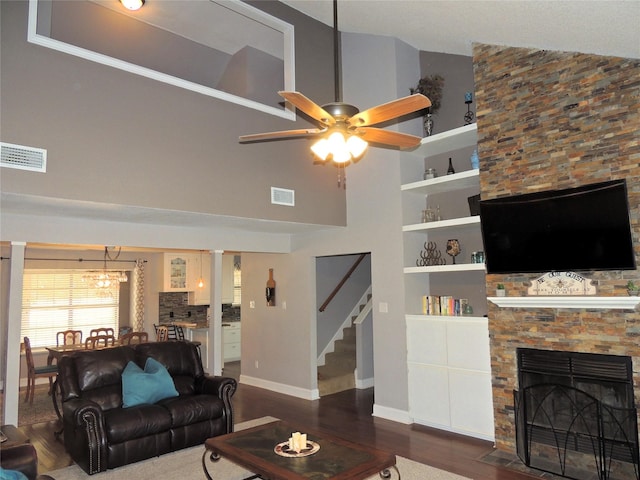 living room featuring ceiling fan, high vaulted ceiling, built in features, a fireplace, and dark hardwood / wood-style floors