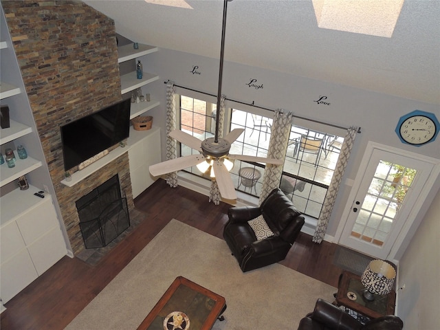 living room with vaulted ceiling, ceiling fan, built in features, a textured ceiling, and a fireplace