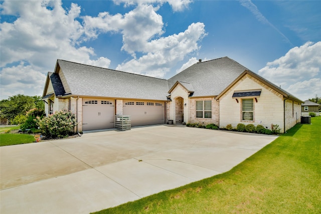 french provincial home with a garage, a front lawn, and central air condition unit