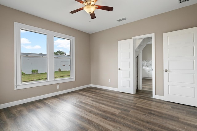 unfurnished bedroom with ensuite bath, ceiling fan, and dark wood-type flooring