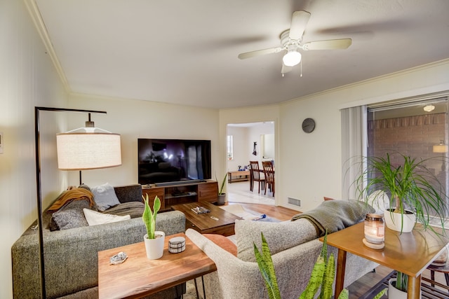 living room with ornamental molding, wood-type flooring, and ceiling fan