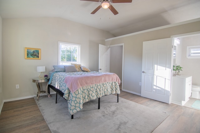 bedroom with ensuite bath, ceiling fan, light hardwood / wood-style flooring, and vaulted ceiling