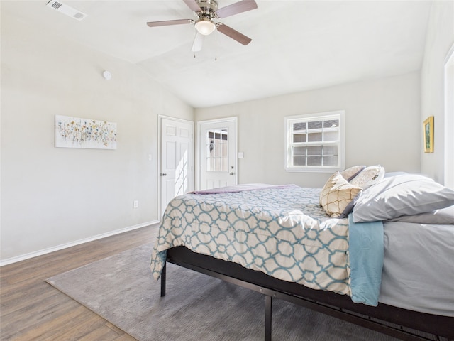 bedroom featuring vaulted ceiling, wood finished floors, visible vents, and baseboards