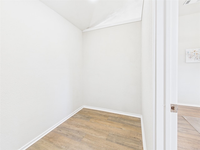 unfurnished room with vaulted ceiling, baseboards, and wood finished floors