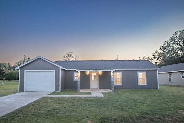 ranch-style home featuring a yard, concrete driveway, a garage, and a shingled roof